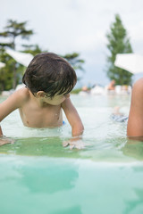 Young boy kid child splashing in swimming pool having fun leisur