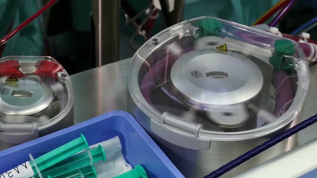 Cardiac surgeons performing a cardiac surgery. Surgeon's assistant removing healthy blood vessel from the leg in the foreground