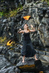 Girl in a black suit with flaming torches .