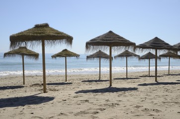 Row of straw umbrellas in Marbella, Spain