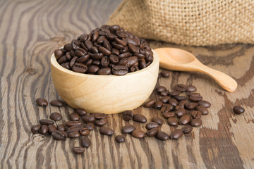 Coffee beans in wood spoon and on old wood table