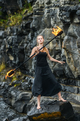 Girl in a black suit with flaming torches .