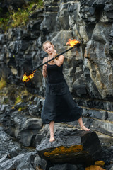 Girl in a black suit with flaming torches .