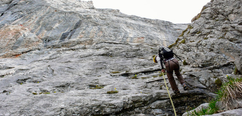 a mountain guide rappelling to the start of a climbing route in the Churfirsten mountains in the...