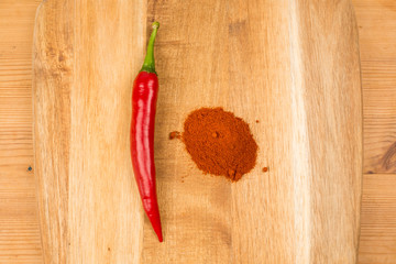 Milled and fresh chili peppers on a wooden board