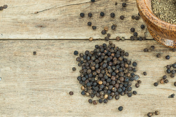 black pepper on wooden table texture with grounded black pepper in wooden mortar, close up, copy space