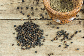 black pepper on wooden table texture with grounded black pepper in wooden mortar, close up
