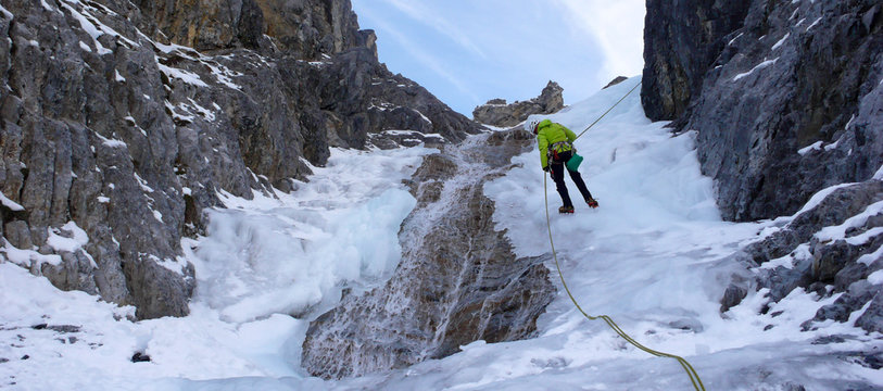 an ice climber rappelling on an ice fall in the Swiss Alps