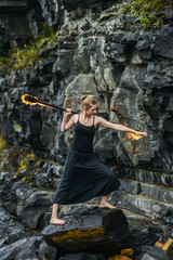 Girl in a black suit with flaming torches .