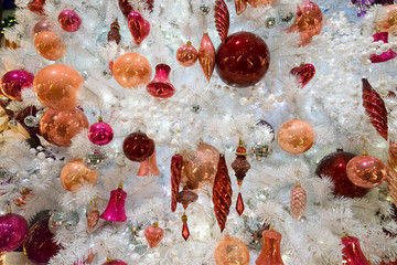 christmas white tree with holiday red and orange decorations and lights close up