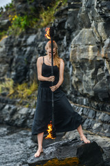 Girl in a black suit with flaming torches .