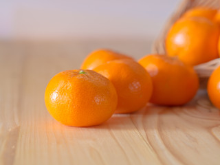 Oranges on Wicker basket, on pine wooden table.