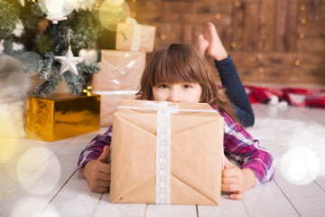 Fototapeta na wymiar Little girl with Christmas gifts near a Christmas tree