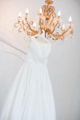 Wedding dress on the chandelier. Morning of the bride.