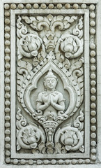 Ancient relief sculpture of deva in Buddhism with lotus flowers. The modeling is visual Buddhist religion arts made of concrete on Thailand temple wall.