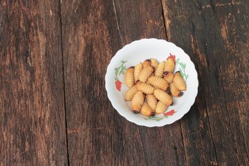 Sago beetle worm, Red palm weevil, Fried in cup (Rhynchophorus ferrugineus) Popular food larva  Southern Thailand on the wooden floor
