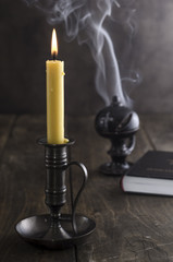 Obraz na płótnie Canvas Candlestick and burning candle and in the background a incense