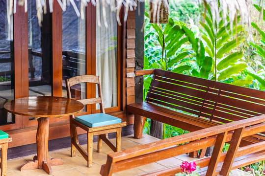 Vintage wooden chairs, benches and table on a home porch. They are traditional furnitures in Thailand, Asia.