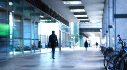 Abstract, blurred image of people walking in long tunnel with light at the background. 