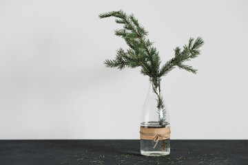 Christmas decorations on tha table, spruce branch in the bottle