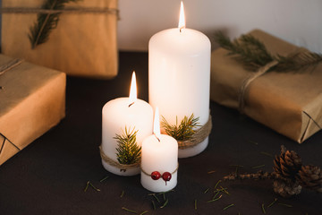Christmas decorations on tha table, lit candles and gifts