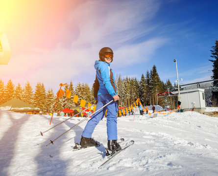 Female skier on the top of ski slope on a sunny day at ski resort. Woman is smiling and looking at the camera. Carpathian mountains.