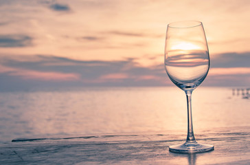 Glass of wine on a wooden table seaside sunset style sweet tone. The concept Romantic Dinner.Sea glass of wine.Background blurred ocean
