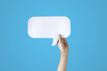 Human Hands Holding White Speech Bubble Over Blue Background - Balloon speech bubble concept