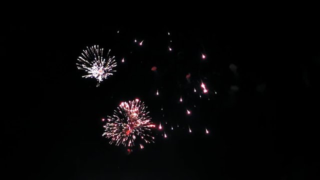 Colorful fireworks in the night sky. Red, blue and green flashes. Clouds of smoke.