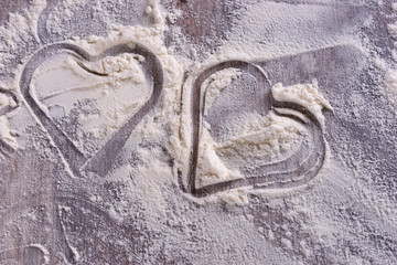 Heart from a cookie cutter in flour on wooden table