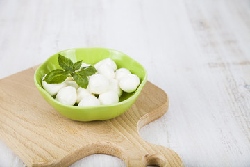 Mozzarella in a green plate on a wooden table. Delicious fresh c