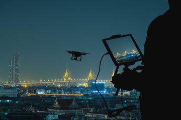 Silhouette of Man using drone to monitor the city at night.