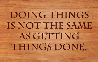 Doing things is not the same as getting things done - a quote on wooden red oak background