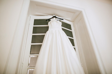 Fototapeta na wymiar White Wedding dress on a shoulders on door, before ceremony