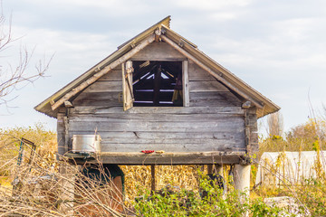 Rustic wood shack on stilts in the fall field with dry grass and blue sky background 