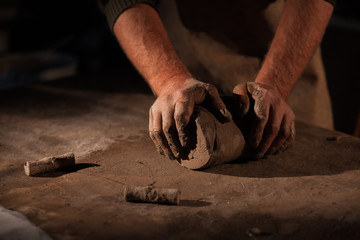 Hands of the potter knead clay.