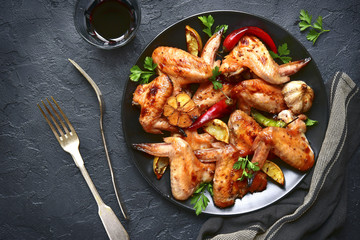 Grilled chicken wings on a black plate.Top view.