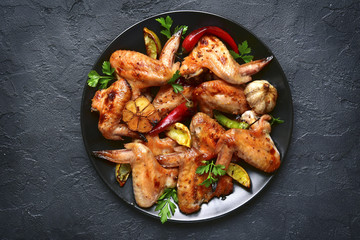 Grilled chicken wings on a black plate.Top view.