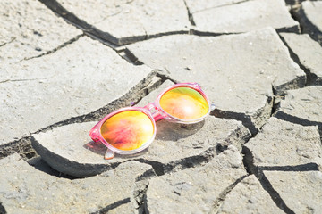 Pink sunglasses on dry  cracked ground