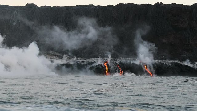 Lava flowing into the ocean from lava volcanic eruption on Big Island Hawaii, USA. Lava stream flowing in Pacific Ocean from Kilauea volcano, USA. Seen from water, Steadicam, 59.94 FPS, 2016.
