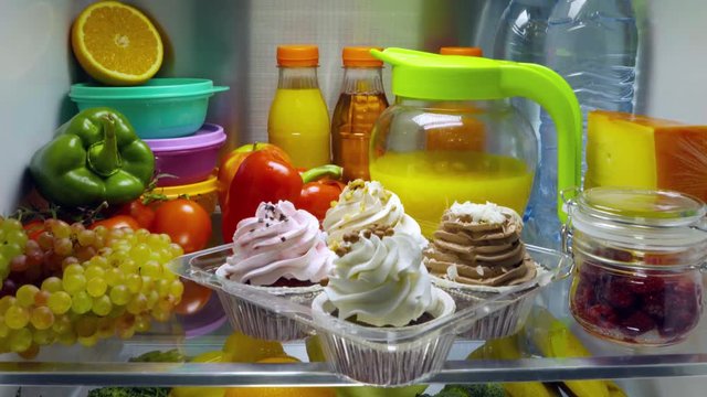 Sweet cakes in the open refrigerator. Products in the refrigerator.