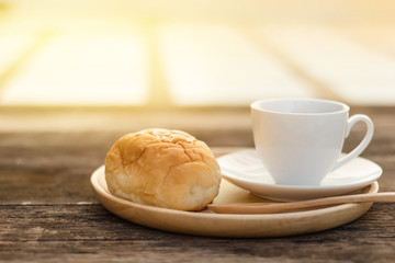 coffee mug with slice bread and wooden spoon on wood plate and rustic table in the morning with sunlight, breakfast