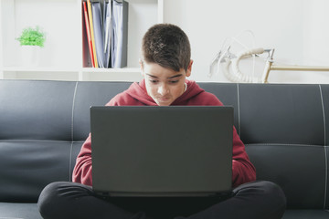child with computer laptop sitting in the sofa of house
