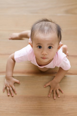 Beautiful smiling asian baby girl while crawling up a stair.