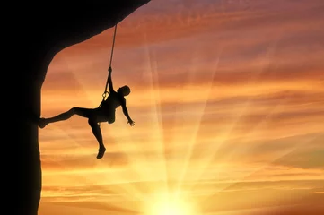 Foto op Canvas Mountaineer climbing on rock on sunset background © Prazis Images