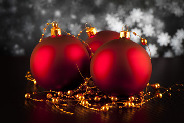 Three red Christmas baubles on black table