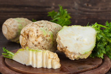 Organic celery, root celery and leaves of celery on a wooden board