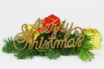 Golden Merry Christmas sign with miniature gift boxes on fresh pine

