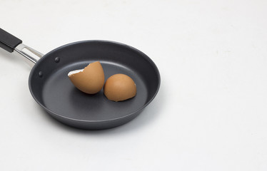 Eggshell on iron frying pan isolated white background