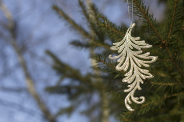 Silver Christmas toy hanging on a natural tree closeup